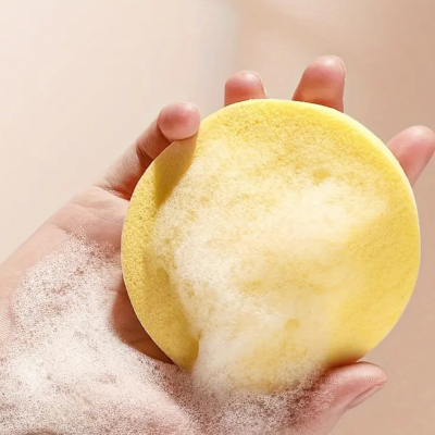 Esponja de banho amarela com espuma na mão
