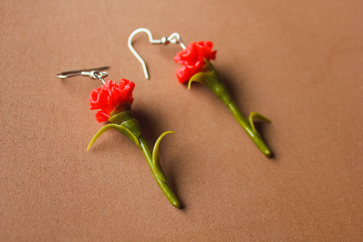 Brincos Cravos Brincos em forma de flor vermelha com caule verde em superfície castanha