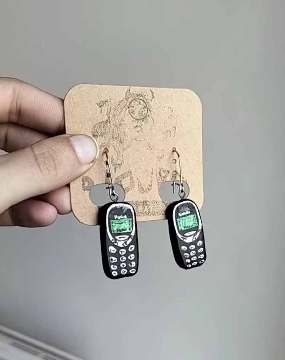 Brincos Nokia Brincos com design de telemóveis antigos pretos e verdes em cartão castanho com desenho de cão.