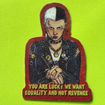 Autocolante de personagem punk com cabelo metade preto metade branco e texto sobre igualdade