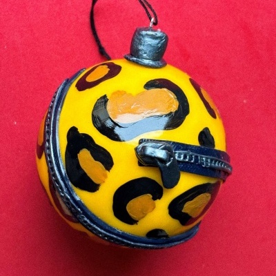 Bola decorativa amarela com manchas pretas e castanhas e detalhes metálicos