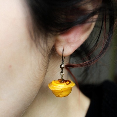 Brinco amarelo em forma de pastel de nata pendurado na orelha