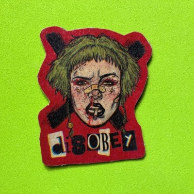 Adesivo vermelho com rosto feminino desenhado e texto disOBEY