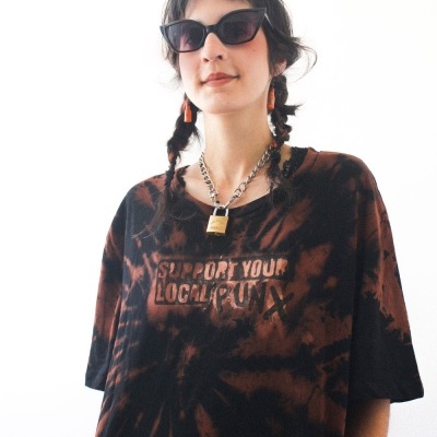 Pessoa com óculos de sol e t-shirt tie-dye preta e laranja com texto