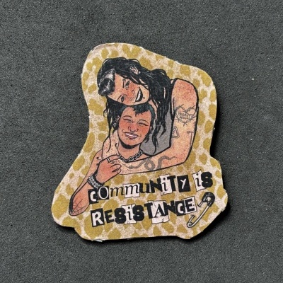 Autocolante com ilustração de duas pessoas e texto COMMUNITY IS RESISTANCE