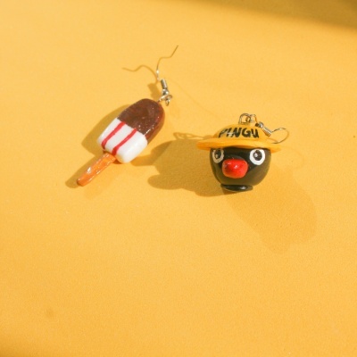 Par de brincos desenhados, gelado e cabeça de pinguim com chapéu amarelo