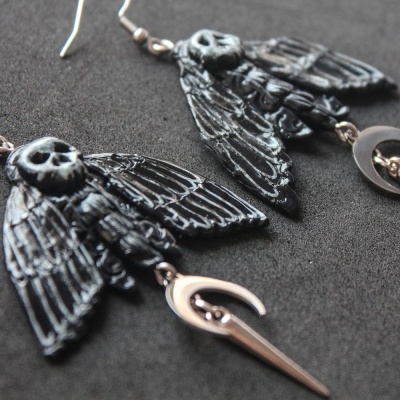 Brincos metálicos com caveira, asas pretas e pendentes de meia-lua e lâmina