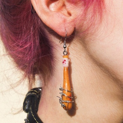 Brinco pendente formato taco laranja com arame prateado e colar preto de spikes no pescoço