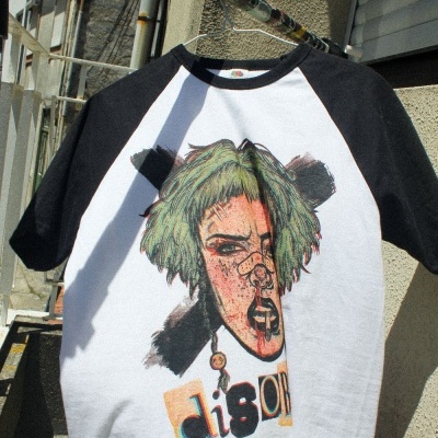 T-shirt branca e preta com estampa de rosto colorido e texto disorder pendurada num cabide