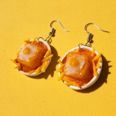 Brincos artificiais em forma de prato com massa e ovo de manhã sobre fundo amarelo