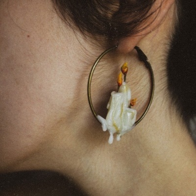 Brinco aro metálico dourado com velas derretidas brancas e chamas laranja