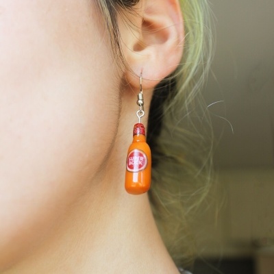 Brinco de garrafa laranja com rótulo SUPER BOCK e colar de corrente prateada