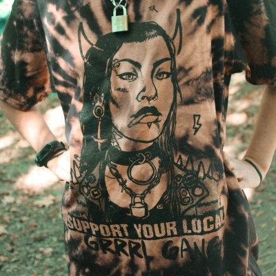 T-shirt tie-dye castanha e preta com estampa de mulher com chifres e texto Grrrl Gang