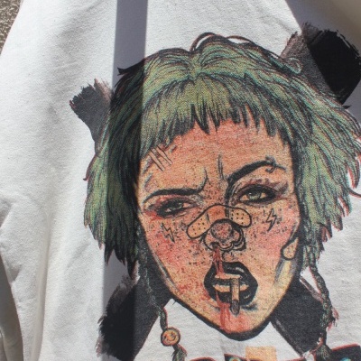 Camisola branca com imagem colorida de rosto de mulher e texto colorido em baixo.