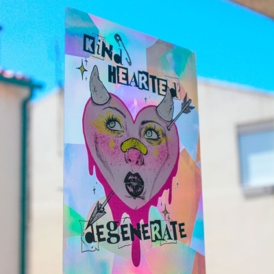 Cartaz decorativo holográfico com coração rosa e texto kind HEARTED degenerate