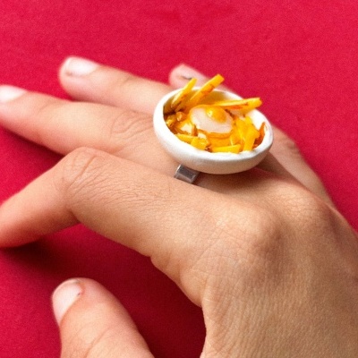 Anel com miniatura de prato de comida em fundo vermelho