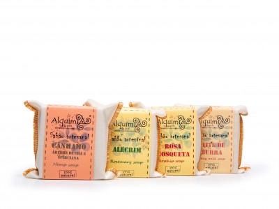 Quatro sabonetes artesanais Alquim com embalagens coloridas em laranja, verde, amarelo e bege