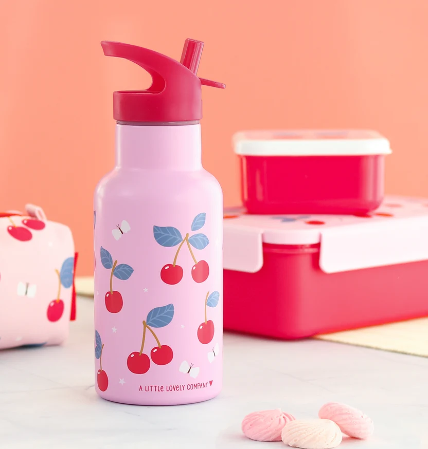 Garrafa de aço inoxidável: Cerejas Garrafa rosa com padrão de cerejas e tampa vermelha ao lado de caixas vermelhas e biscoitos moles.
