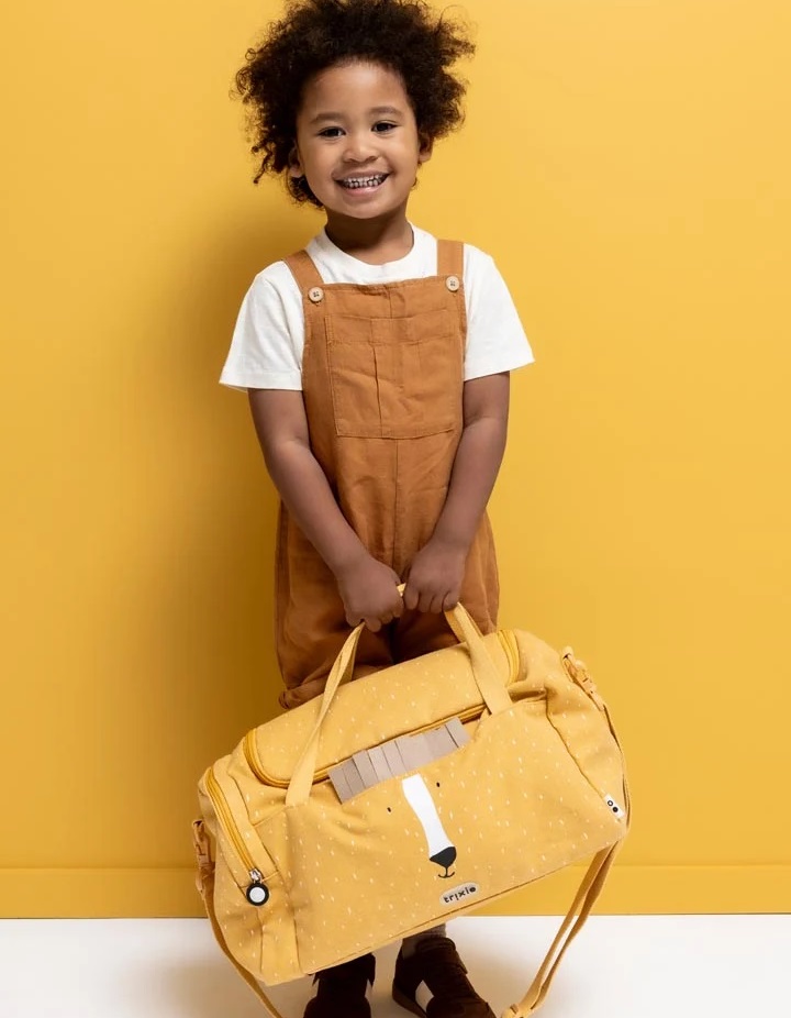 Mochila de ginástica infantil - Mr. Lion Criança a segurar mala de viagem amarela com padrão e rosto de animal, em fundo amarelo