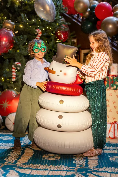 Balão boneco de neve Crianças com boneco de neve insuflável em ambiente natalício decorado.