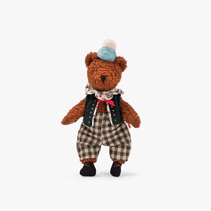 Ursinho de peluche vestido com calças aos quadrados, colete, lenço e chapéu azul com pompom