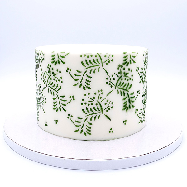 Stencil Olivia Bolo redondo branco com padrão de folhas verdes num prato branco