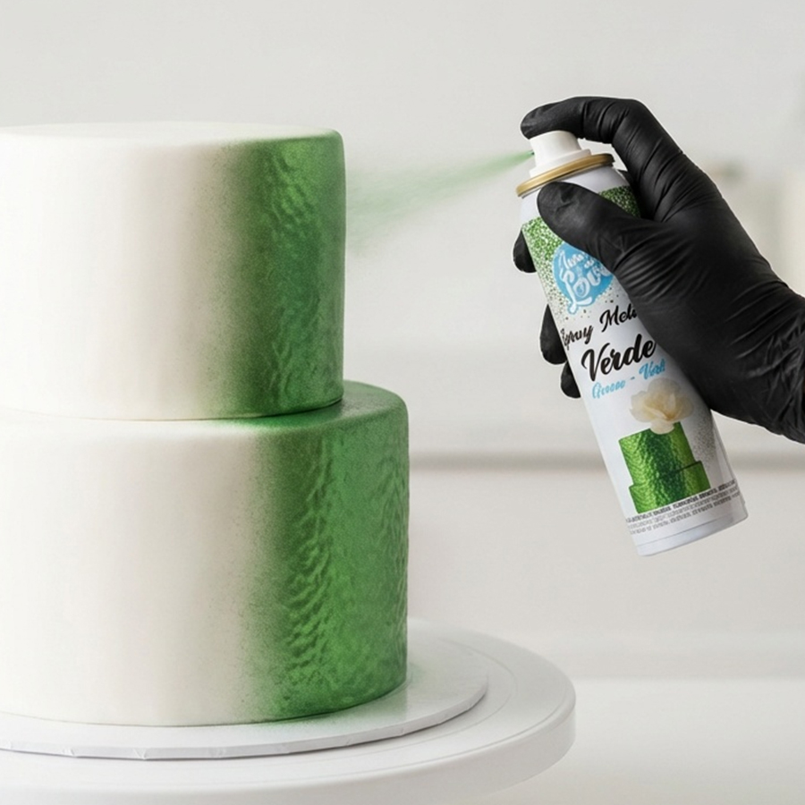 Spray Metallic Verde Mão com luva preta a pintar bolo branco com spray verde metalizado.