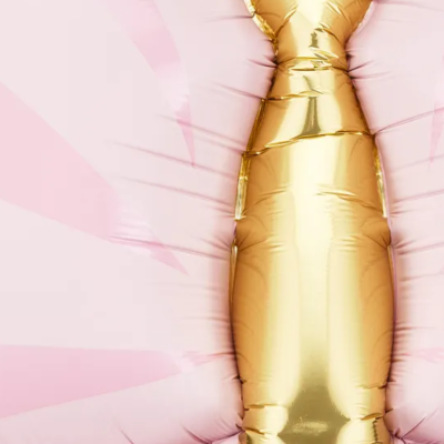 Balão metálico dourado em forma de garrafa sobre fundo rosa com raios