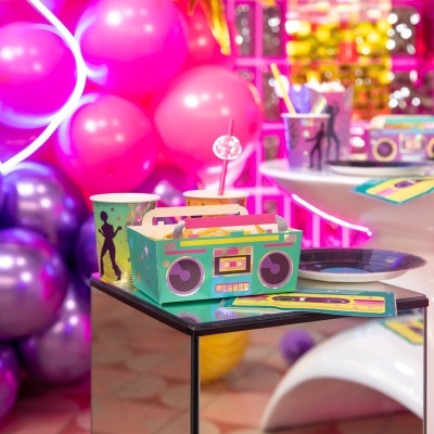 Conjunto de embalagem para festa com caixa decorativa e copos coloridos com balões ao fundo