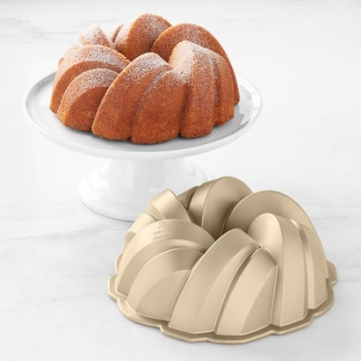 Forma para bolo Bundt dourada e bolo polvilhado sobre base branca
