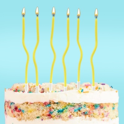 Bolo de aniversário com seis velas amarelas acesas, fundo azul claro