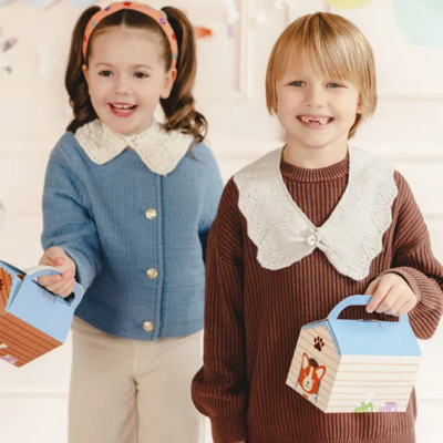 Crianças com caixas de papelão decorativas em ambiente festivo