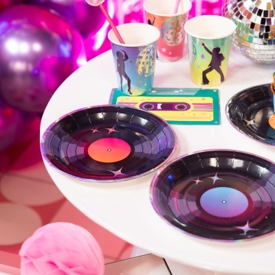 Pratos e copos de papel com tema disco sobre mesa branca