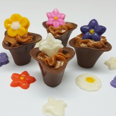 Doces de chocolate em copo decorados com pequenas flores coloridas