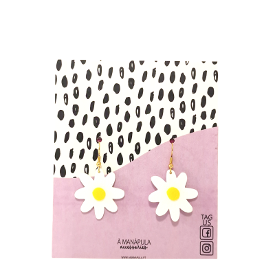 Brincos de margarida em cartão decorativo com manchas negras e fundo rosa.