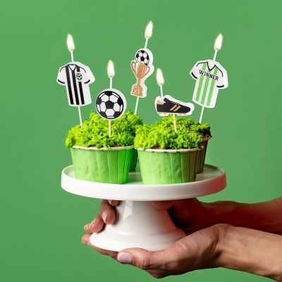 4 cupcakes decorados com velas de futebol em suporte branco