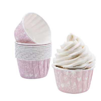 Forminhas rosas para cupcakes com padrão branco, uma contendo creme branco em espiral