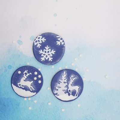 Bolachas decoradas com glacê azul e branco, flocos de neve e veados