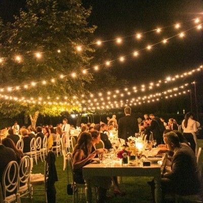 Evento ao ar livre com mesas e luzes pendentes à noite