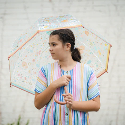 Rapaz com camisa riscada colorida segurando guarda-chuva transparente com padrão floral