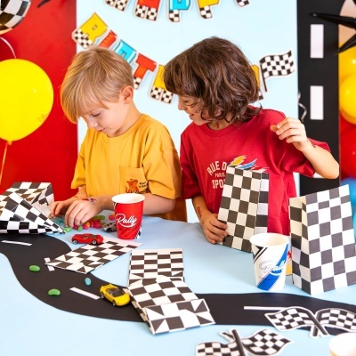 Crianças numa mesa com decoração de corrida e sacos xadrez preto e branco.
