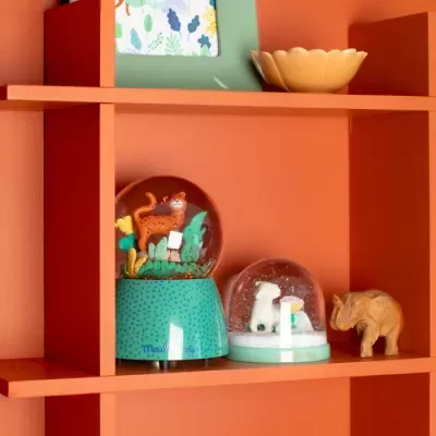 Bolas de neve decorativas e escultura de elefante numa prateleira laranja