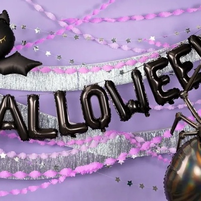 Balões decorativos de Halloween pretos e fitas prateadas e rosa num fundo roxo.