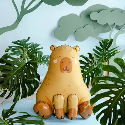 Balão insuflável em forma de urso castanho rodeado por plantas e árvores de papel