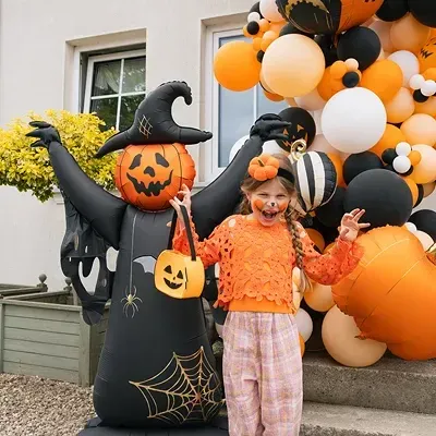 Criança vestida com roupa de Halloween junto a decoração de balões e boneco insuflável de Bruxa Abóbora