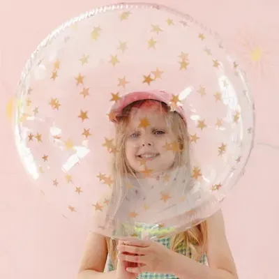 Criança segurando balão transparente com estrelas douradas
