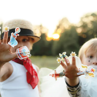 Duas crianças com adesivos coloridos nas mãos em ambiente ao ar livre ao pôr do sol.