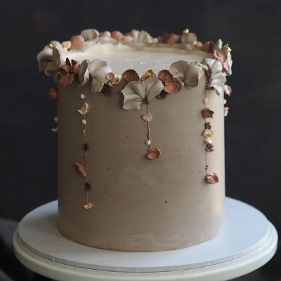 Bolo alto decorado com flores secas e folhas em tons castanhos e bege