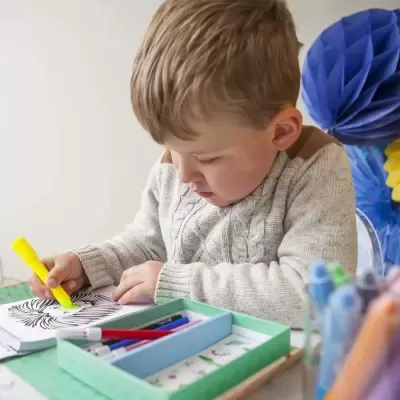 Criança a colorir num livro com marcador amarelo
