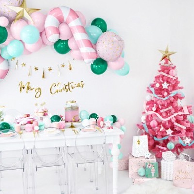Decoração de Natal com árvore rosa, balões coloridos, mesa branca e presentes embalados